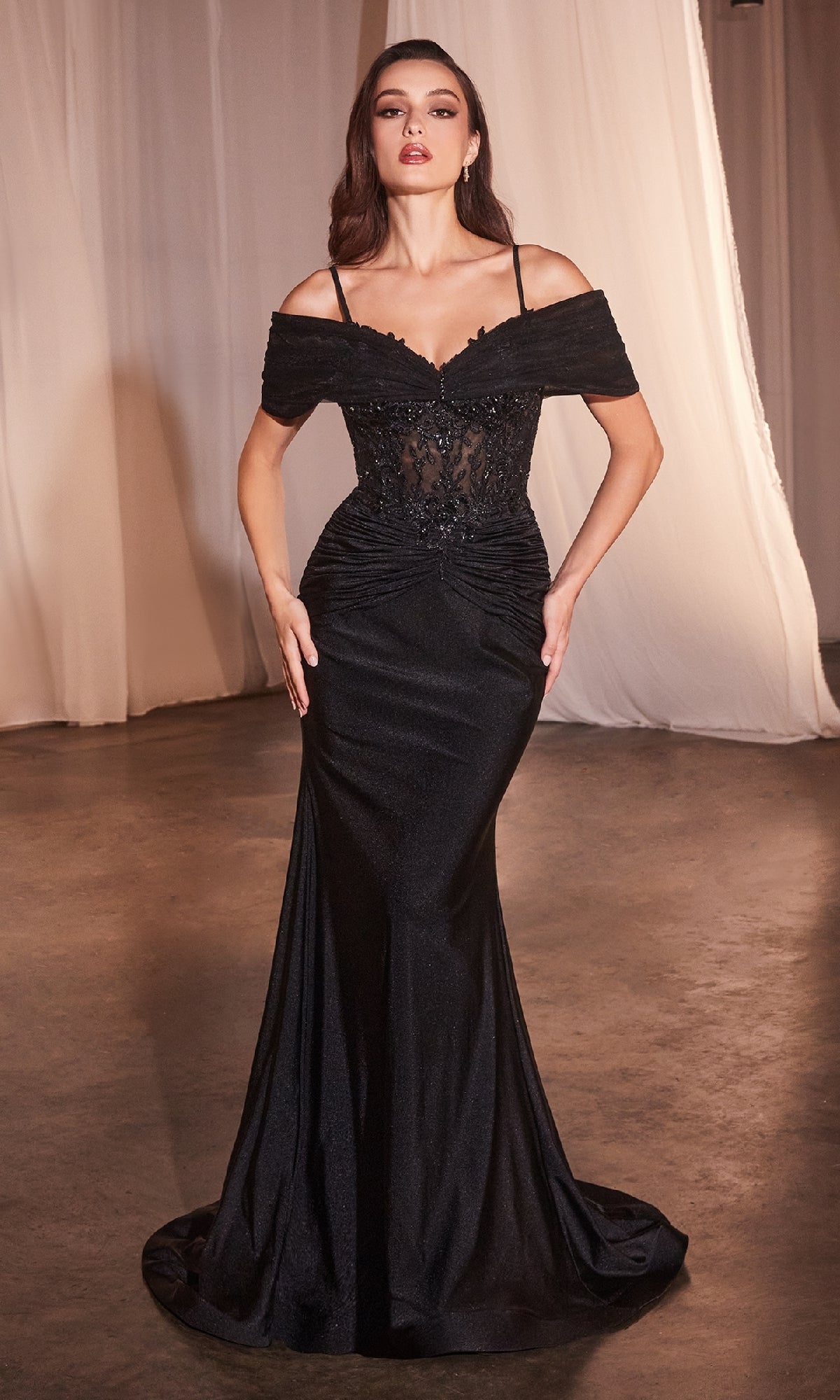 A woman stands indoors wearing the Sheer Lace-Bodice Long Prom Dress (CLCD798), featuring an off-the-shoulder black lace bodice and a floor-length skirt. White curtains are visible in the background.